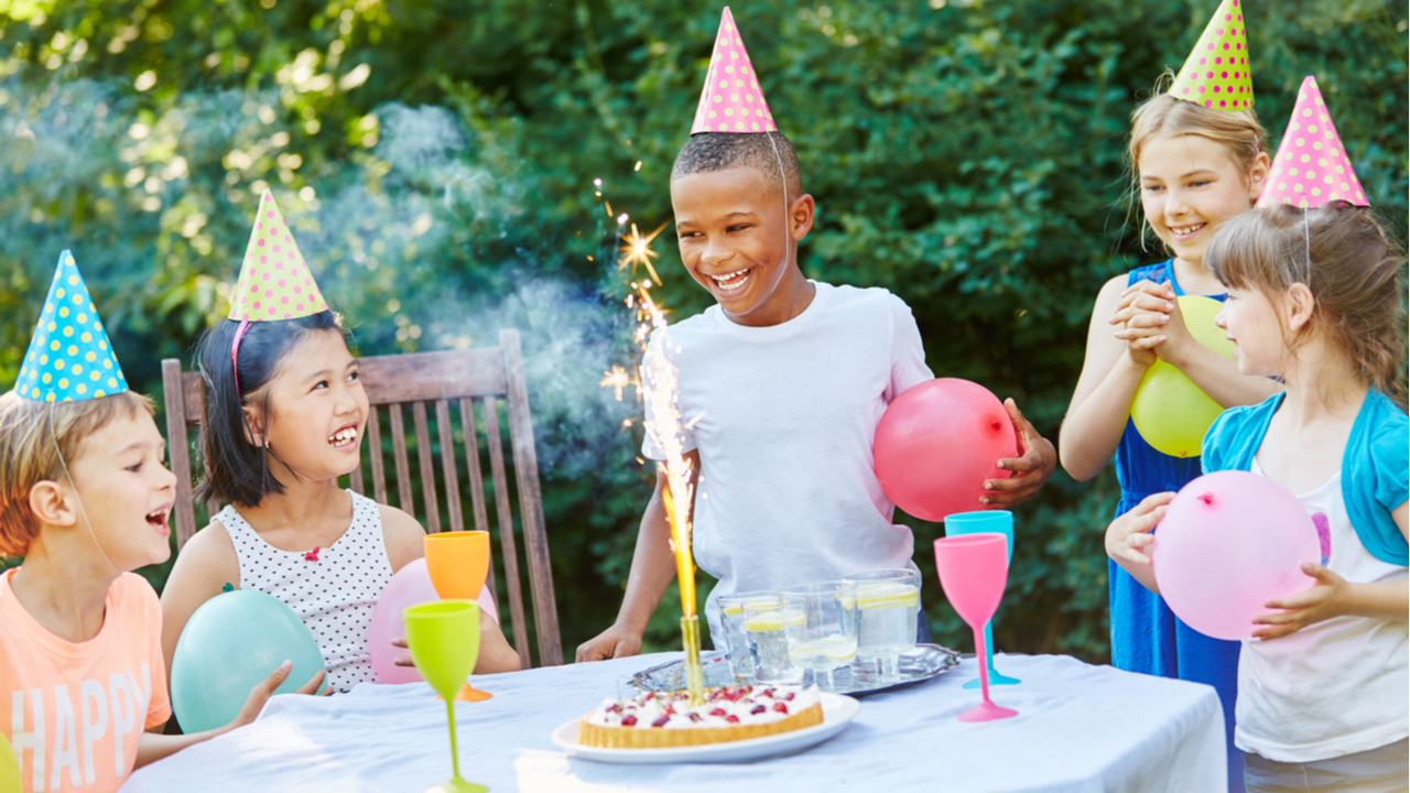 Ein Kindergeburtstag im Freien mit Kuchen und Partyhüten.